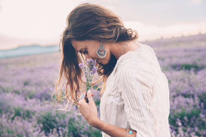 woman breathing deeply into flowers